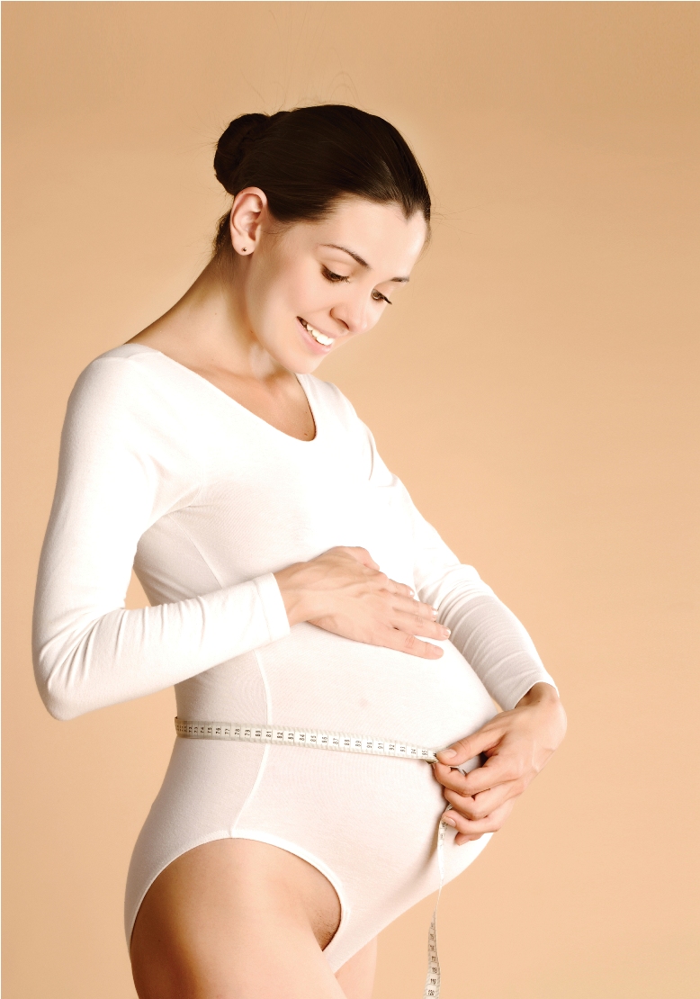 Беременная девушка измеряет живот