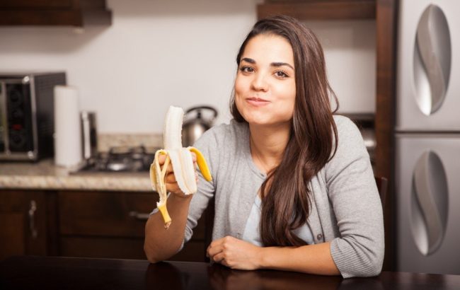 Женщина на кухне и жёлтый банан в руке