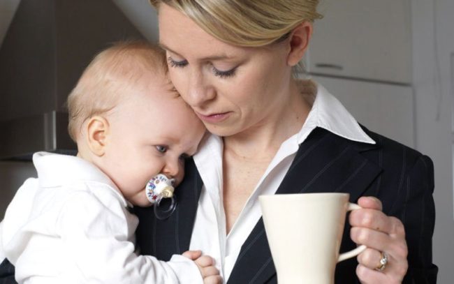 Женщина с младенцем на руках и чашкой кофе