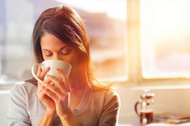 Женщина пьющая кофе из белой чашки