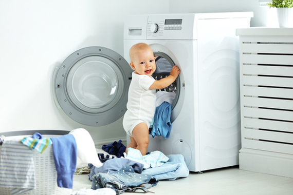 малыш кладет вещи в стиральную машинку