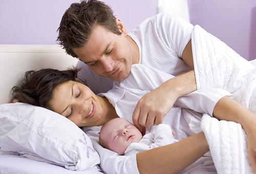 Младенец спит со счастливыми родителями
