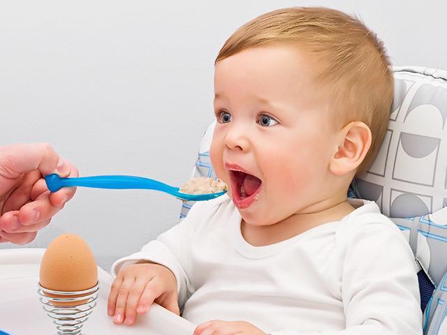 Мальчик кушает яйцо на столике