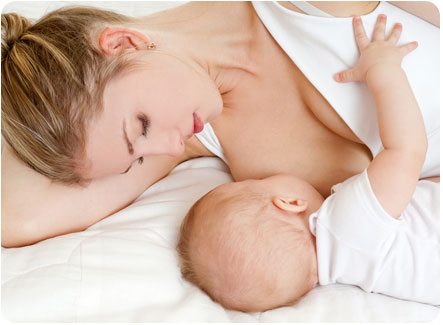 Мама кормит новорожденного ребенка грудью лежа на боку