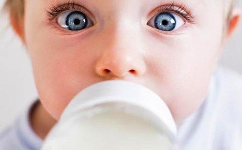 Огромные глаза счастливого ребёнка с бутылочкой молока