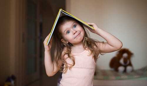 Девочка дурачится с книгой на голове