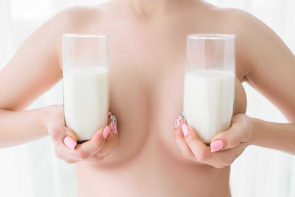 Девушка держит два стакана молока перед грудью