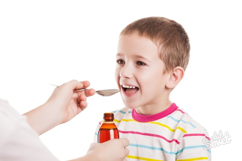 Улыбающийся мальчик принимает лекарственный сироп из ложки в руках врача или родителя