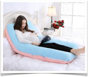 Беременная девушка сидя читает журнал облокотившись на подушку