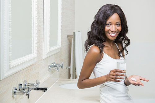 Beautiful woman holding pill and glass of water Beautiful woman holding pill and glass of water